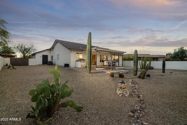 back house at dusk featuring a patio and cooling unit