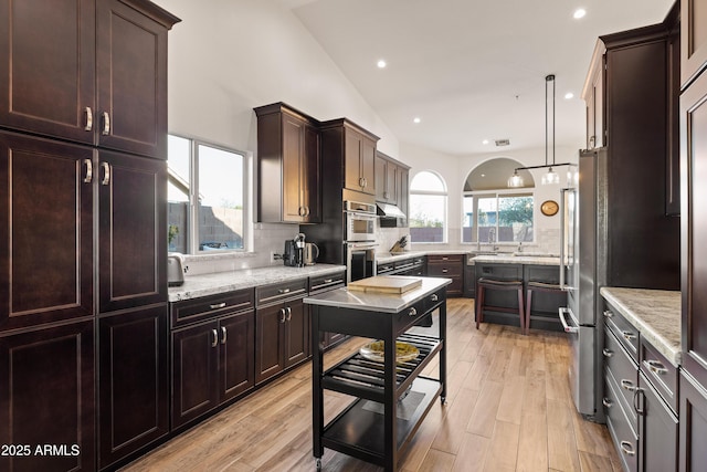 kitchen featuring light stone counters, stainless steel appliances, and backsplash