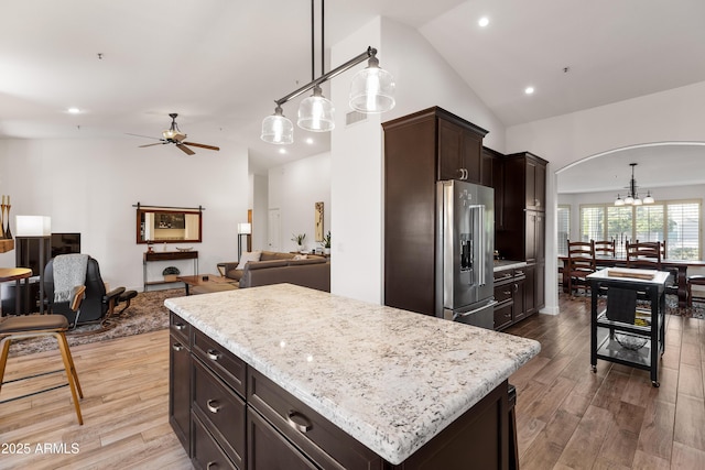 kitchen with hanging light fixtures, a kitchen island, high quality fridge, and light wood-type flooring