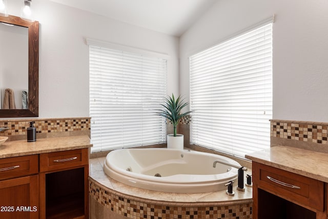 bathroom with vanity, tiled bath, and backsplash