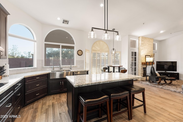 kitchen featuring light stone counters, sink, a kitchen breakfast bar, and a kitchen island