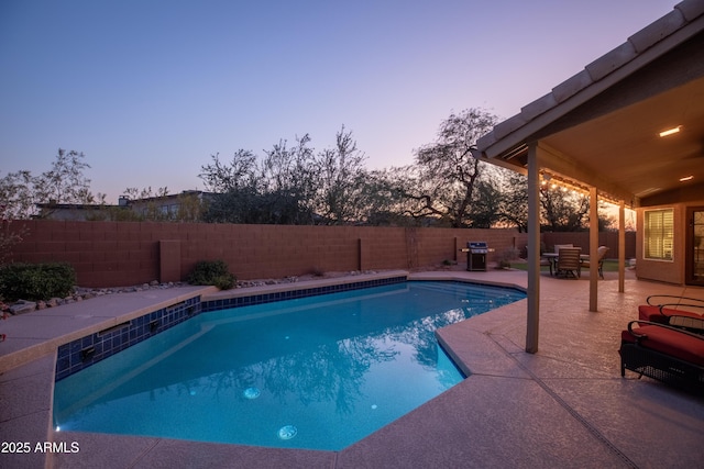 pool at dusk with a grill and a patio area