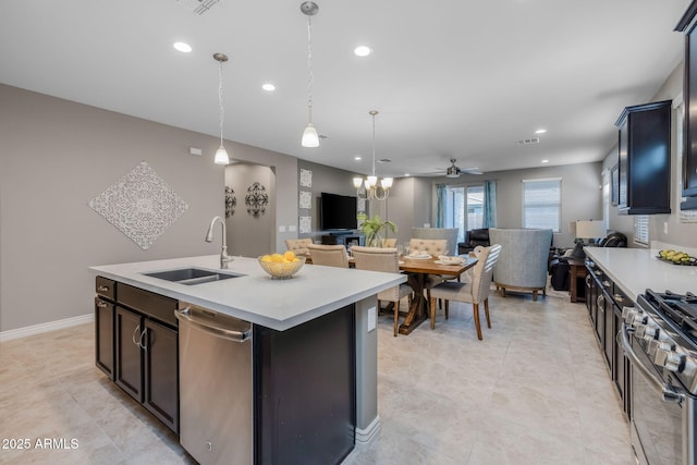 kitchen with recessed lighting, light countertops, a sink, appliances with stainless steel finishes, and open floor plan