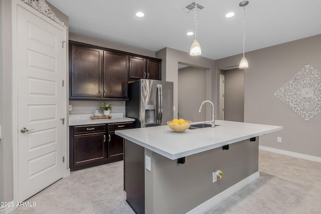 kitchen featuring a sink, visible vents, dark brown cabinetry, stainless steel fridge with ice dispenser, and light countertops