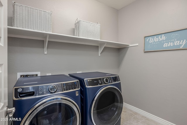 laundry room featuring washing machine and clothes dryer, tile patterned floors, laundry area, and baseboards