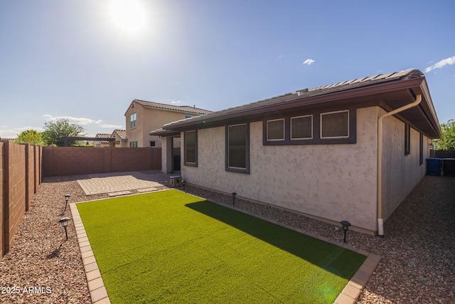 rear view of house with a yard, a patio, a fenced backyard, and stucco siding