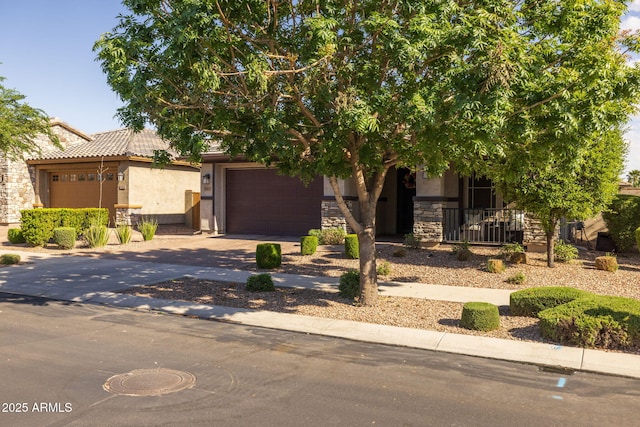 obstructed view of property featuring driveway, stone siding, a tiled roof, a garage, and stucco siding