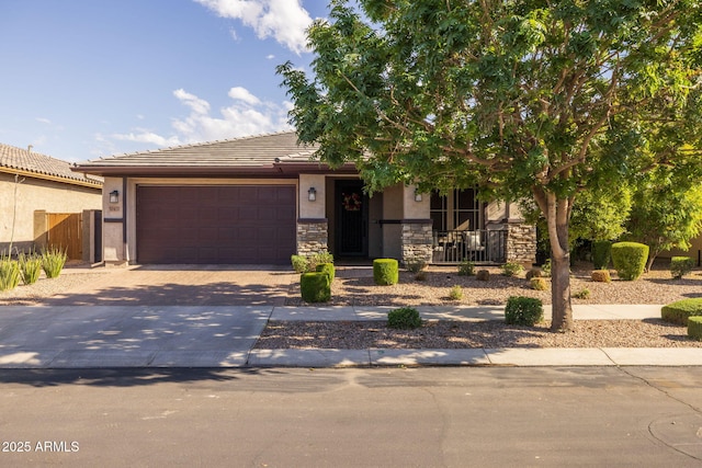 view of front of home with stucco siding, an attached garage, driveway, covered porch, and stone siding