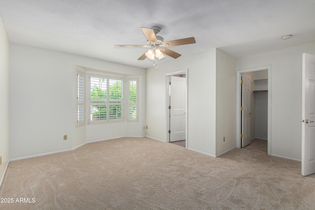 unfurnished bedroom featuring baseboards, a spacious closet, and carpet floors