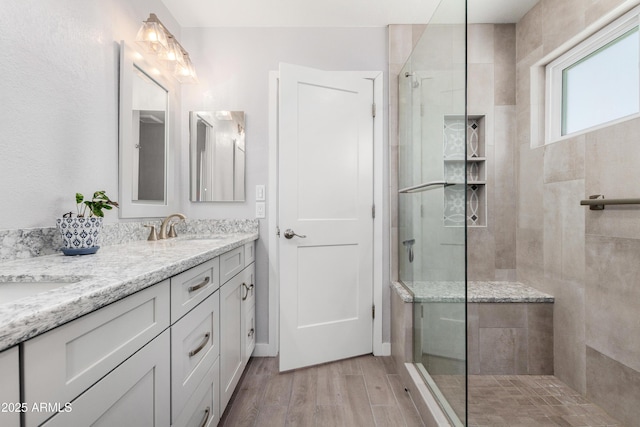 full bath with wood finished floors, walk in shower, double vanity, and a sink