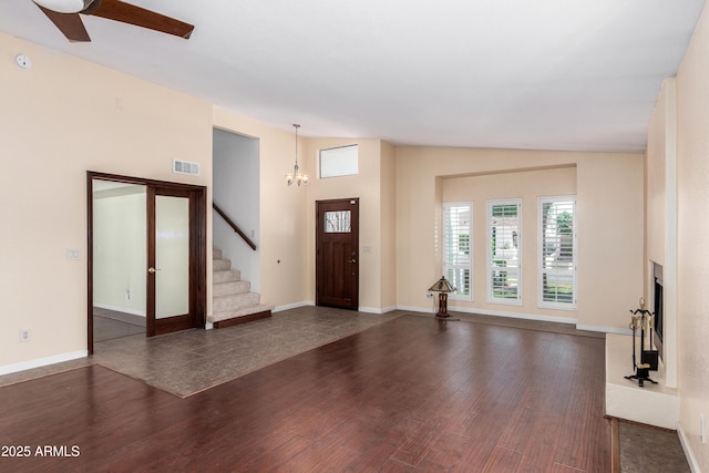 foyer entrance featuring dark wood-style floors, stairway, visible vents, and a fireplace with raised hearth
