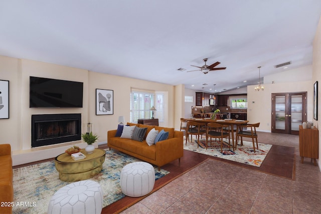 tiled living area with visible vents, a wealth of natural light, ceiling fan, and a fireplace with raised hearth