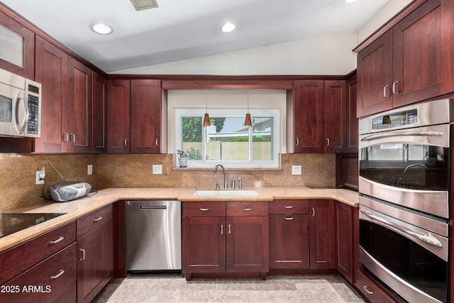 kitchen featuring tasteful backsplash, appliances with stainless steel finishes, vaulted ceiling, a sink, and pendant lighting