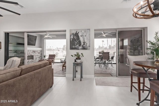 living room with a stone fireplace, plenty of natural light, and ceiling fan