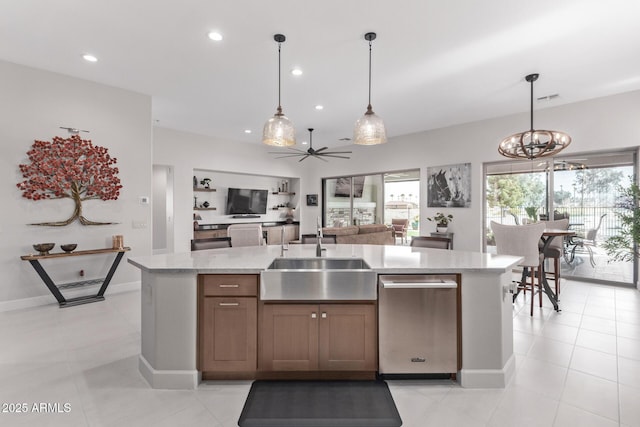 kitchen featuring decorative light fixtures, ceiling fan with notable chandelier, sink, and a kitchen island with sink