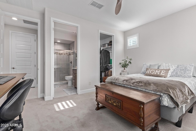 bedroom with light carpet, a walk in closet, ensuite bath, ceiling fan, and a closet