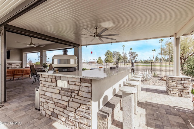 view of patio with exterior kitchen, ceiling fan, and an outdoor bar