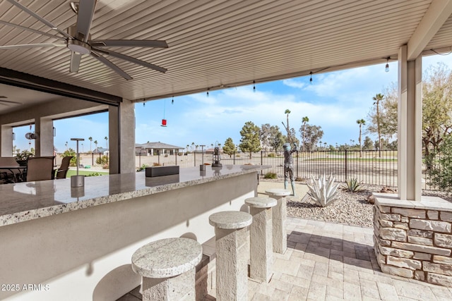 view of patio with ceiling fan and an outdoor bar