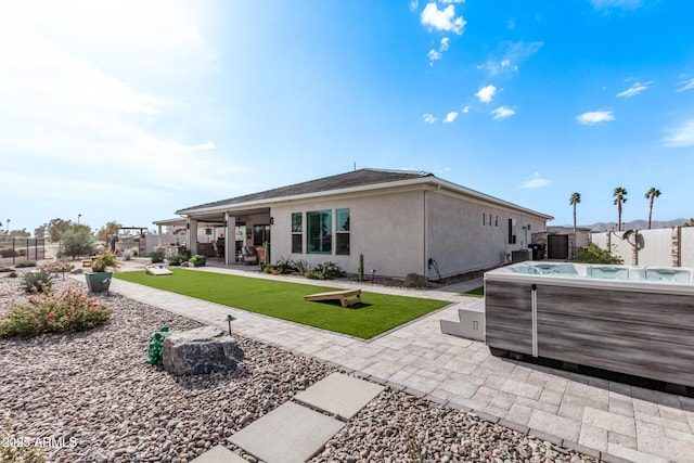 rear view of house with a patio and a hot tub