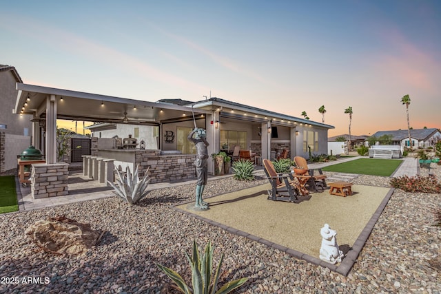 back house at dusk with a fire pit, a patio area, and a bar