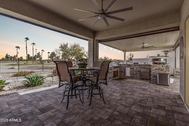 patio terrace at dusk featuring area for grilling and ceiling fan