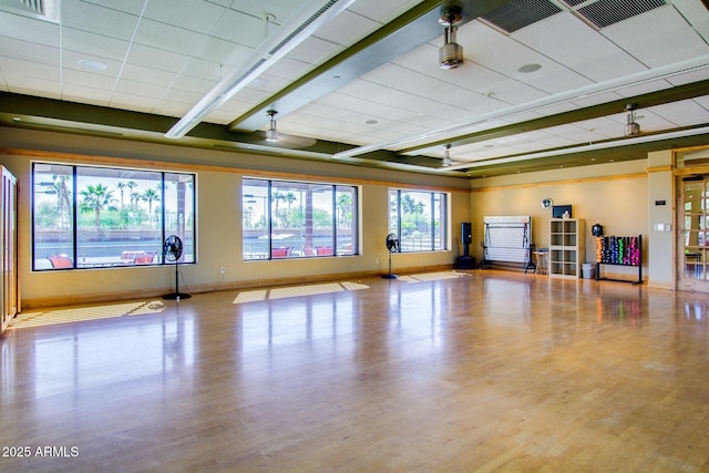 workout area featuring a paneled ceiling and light wood-type flooring