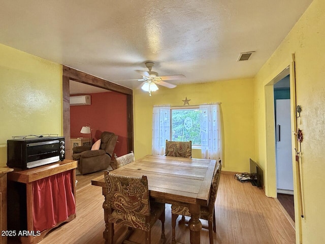 9495 E Marilyn Ln, Dewey, AZ 86327 - dining room featuring a wall mounted AC, light wood-style floors, ceiling fan, baseboard heating, and a textured wall