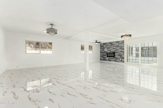 unfurnished living room featuring a tiled fireplace and ceiling fan with notable chandelier