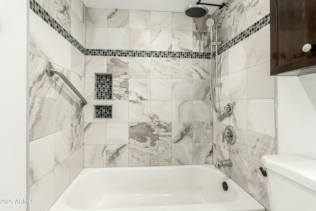 bathroom featuring tiled shower / bath combo and toilet