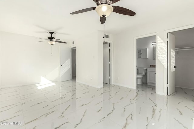 unfurnished bedroom featuring connected bathroom, a walk in closet, a closet, and ceiling fan