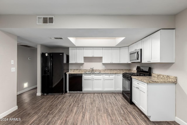 kitchen featuring sink, light stone counters, dark hardwood / wood-style flooring, white cabinets, and black appliances