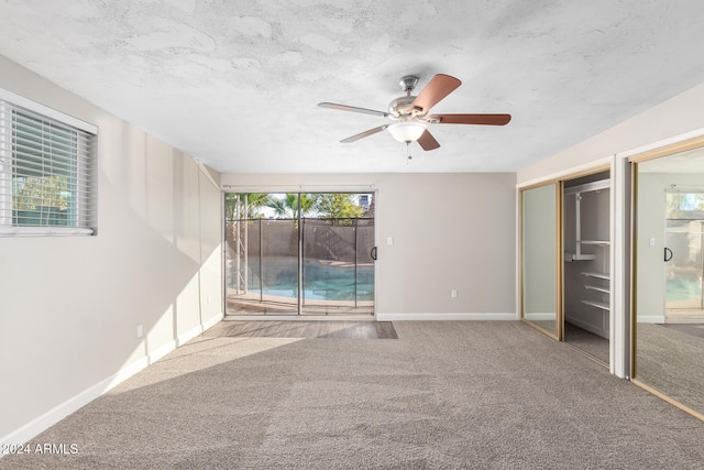 unfurnished bedroom featuring ceiling fan, access to exterior, carpet floors, and multiple windows