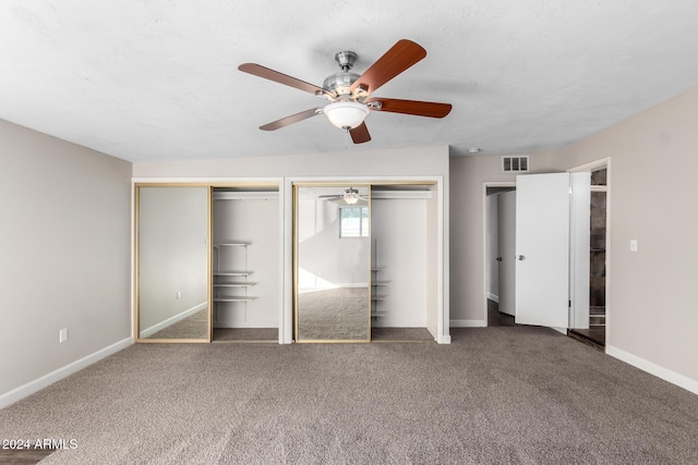 unfurnished bedroom with carpet flooring, multiple closets, and ceiling fan