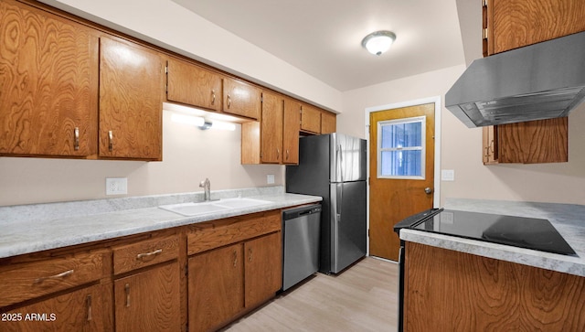 kitchen with brown cabinetry, appliances with stainless steel finishes, light countertops, under cabinet range hood, and a sink