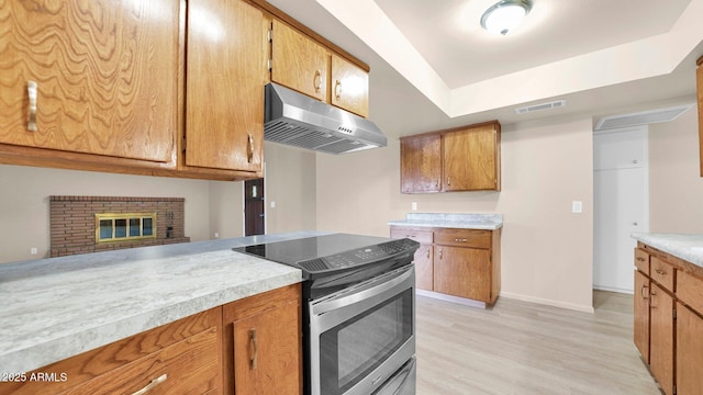 kitchen featuring electric stove, brown cabinets, light countertops, visible vents, and under cabinet range hood