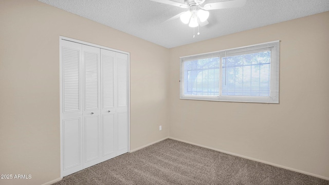 unfurnished bedroom featuring carpet floors, a closet, a ceiling fan, a textured ceiling, and baseboards