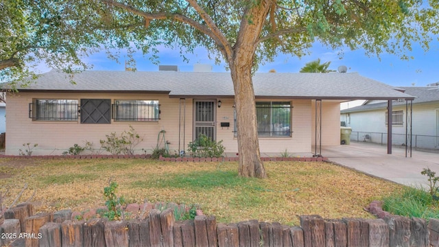 single story home with an attached carport, a front yard, fence, and brick siding