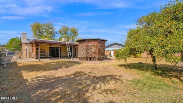 back of property with a chimney, a patio area, and fence