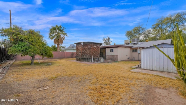 view of yard with a fenced backyard, an outdoor structure, and central air condition unit