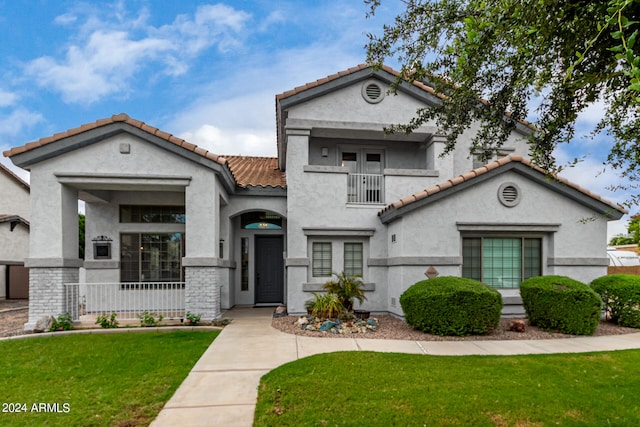 mediterranean / spanish-style house featuring a balcony and a front yard