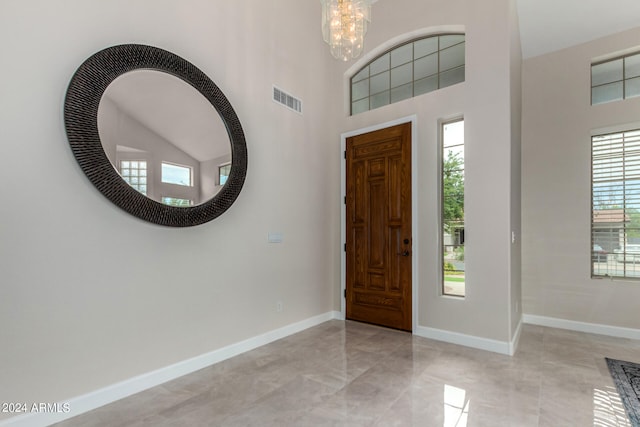 entryway featuring light tile patterned floors, an inviting chandelier, a high ceiling, and a healthy amount of sunlight