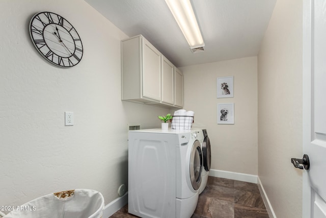 laundry area featuring dark tile patterned flooring, cabinets, and washer and dryer