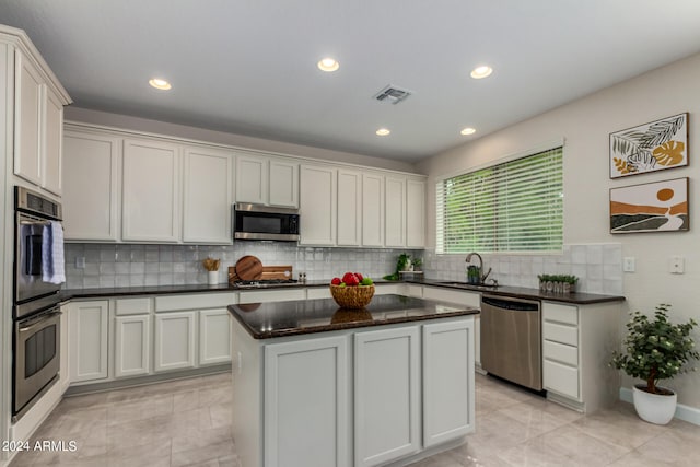 kitchen with a center island, backsplash, appliances with stainless steel finishes, and light tile patterned flooring