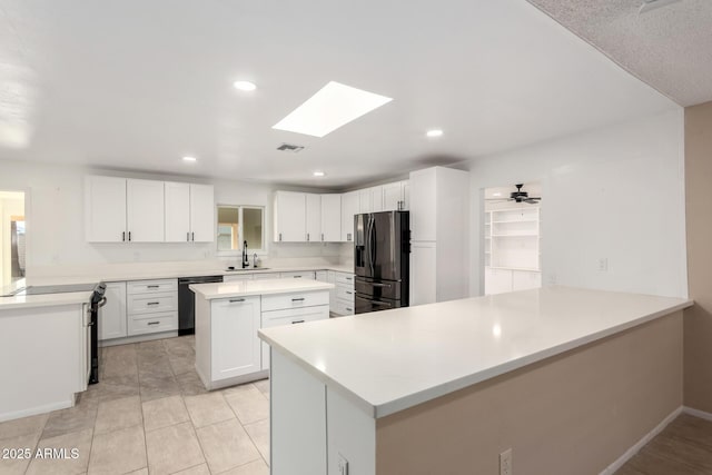 kitchen featuring sink, stainless steel fridge, white cabinetry, black dishwasher, and kitchen peninsula