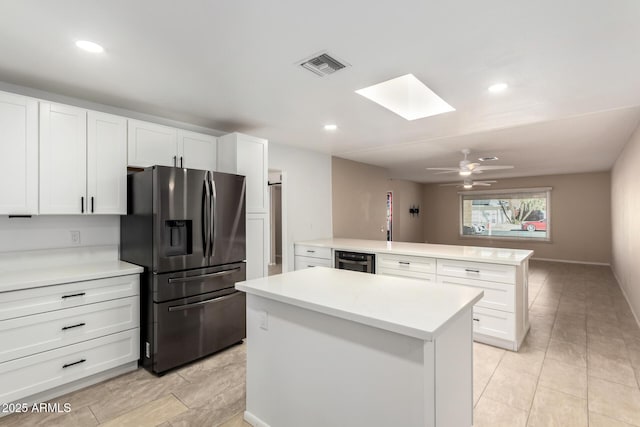 kitchen with white cabinetry, a center island, kitchen peninsula, refrigerator with ice dispenser, and ceiling fan