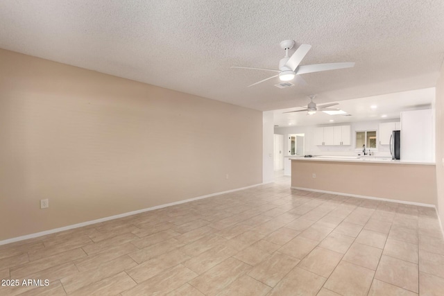 unfurnished living room with sink, a textured ceiling, and ceiling fan