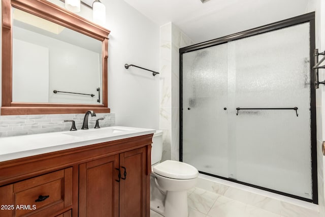 bathroom with tasteful backsplash, vanity, a shower with door, and toilet