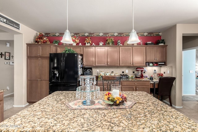 7015 W Melody Dr, Laveen, AZ 85339 - kitchen with black fridge, light tile patterned floors, tasteful backsplash, hanging light fixtures, and light stone counters
