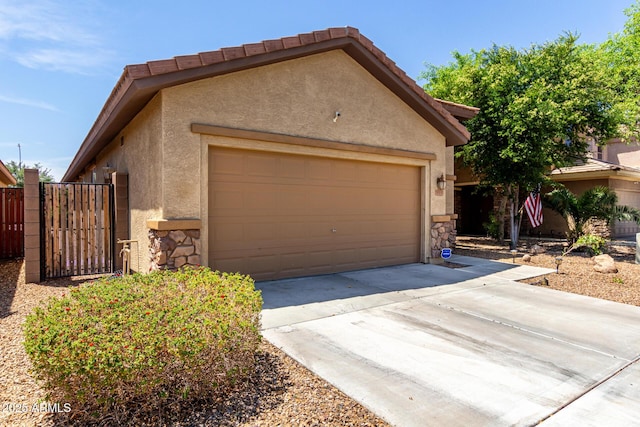 7015 W Melody Dr, Laveen, AZ 85339 - view of front of property featuring stucco siding, stone siding, concrete driveway, a gate, and an attached garage