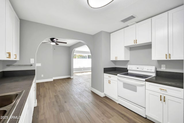 7039 N 15th St, Phoenix, AZ 85020 - kitchen with white range with electric stovetop, dark countertops, visible vents, arched walkways, and wood finished floors